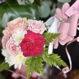 A beautiful handheld bouquet with pink roses, white mums, and a bright fuchsia bloom, finished with greenery and a decorative pink bow. Perfect for quinceañeras, birthdays, and special celebrations.