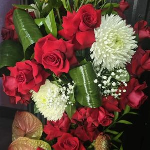 A luxurious red and white tribute featuring roses, chrysanthemums, tropical greens, and elegant accent blooms—perfect for expressing deep love and remembrance.